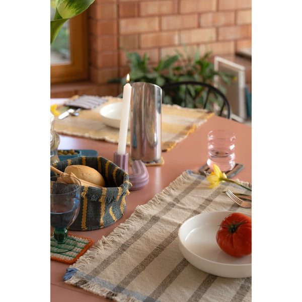Table setting with cloth placemats and bowls and a soft bread basket 