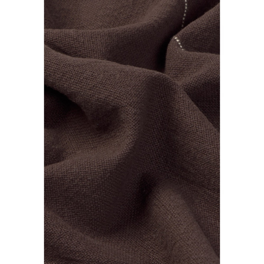 A close-up of dark brown textured napkin with soft folds and a small visible white stitched detail.