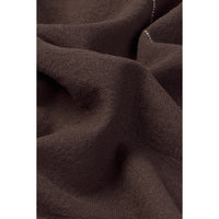 A close-up of dark brown textured napkin with soft folds and a small visible white stitched detail.