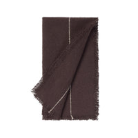 A dark brown woven napkin with fringed edges and a thin white stitched detail, folded neatly on a solid white background.