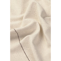 A close-up of draped off-white or cream napkin with a visible dark stitched seam running diagonally through the lower-left area.