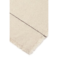 Close-up of a cream-colored woven napkin, showing a textured weave and a fringed edge with a dark stitched detail.