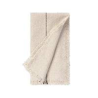 A folded cream-colored woven napkin with fringed edges and a single dark vertical stripe detail, shown on a solid white background.