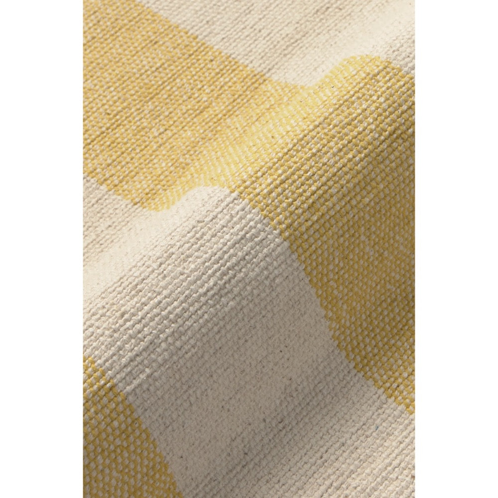 A close-up of a woven textile with a soft chevron pattern in pale yellow and warm off-white, showing the detailed texture of the fabric.