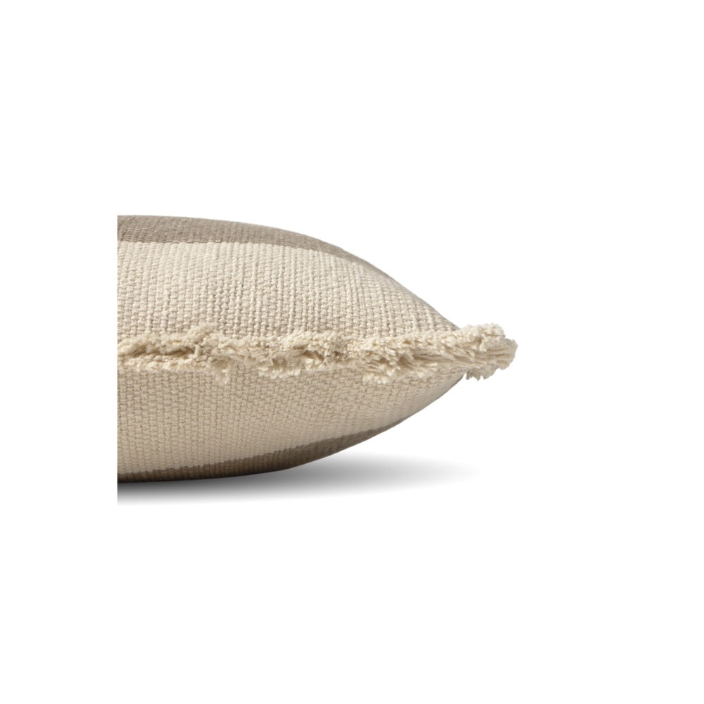 A close-up side view of a textured beige throw pillow with a frayed, tasseled edge, set against a plain white background.