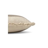 A close-up side view of a textured beige throw pillow with a frayed, tasseled edge, set against a plain white background.