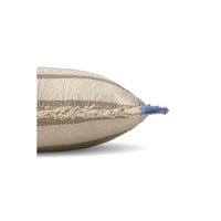 A close-up side view of a woven throw pillow in beige and taupe stripes with a blue tassel at the pointed end, shown on a white background.