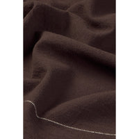 A close-up of dark brown tablecloth with a fine white dotted line running alongh the lower edge.