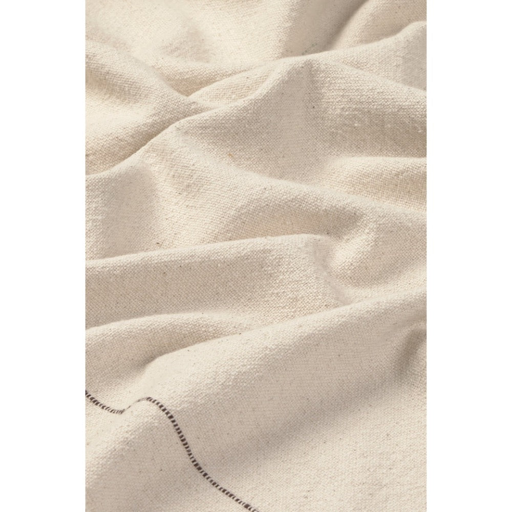 A close-up of draped off-white or cream tabelecloth with a visible woven texture and a short section of dark stitched edge near the bottom.
