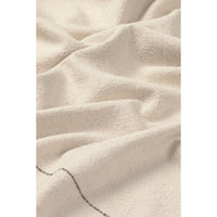 A close-up of draped off-white or cream tabelecloth with a visible woven texture and a short section of dark stitched edge near the bottom.
