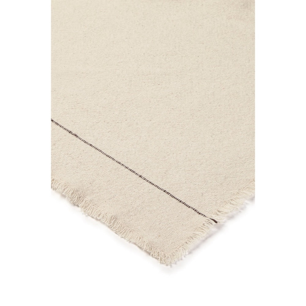 Close-up of a cream-colored woven tablecloth, showing a fringed edge and a thin dark stitched detail against a white background.