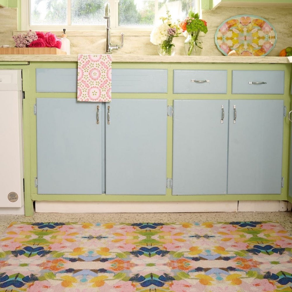 Colorful kitchen with pastel blue cabinets, vibrant accents, and a Laura Park Designs Color Me Happy Floor Mat by the sink.