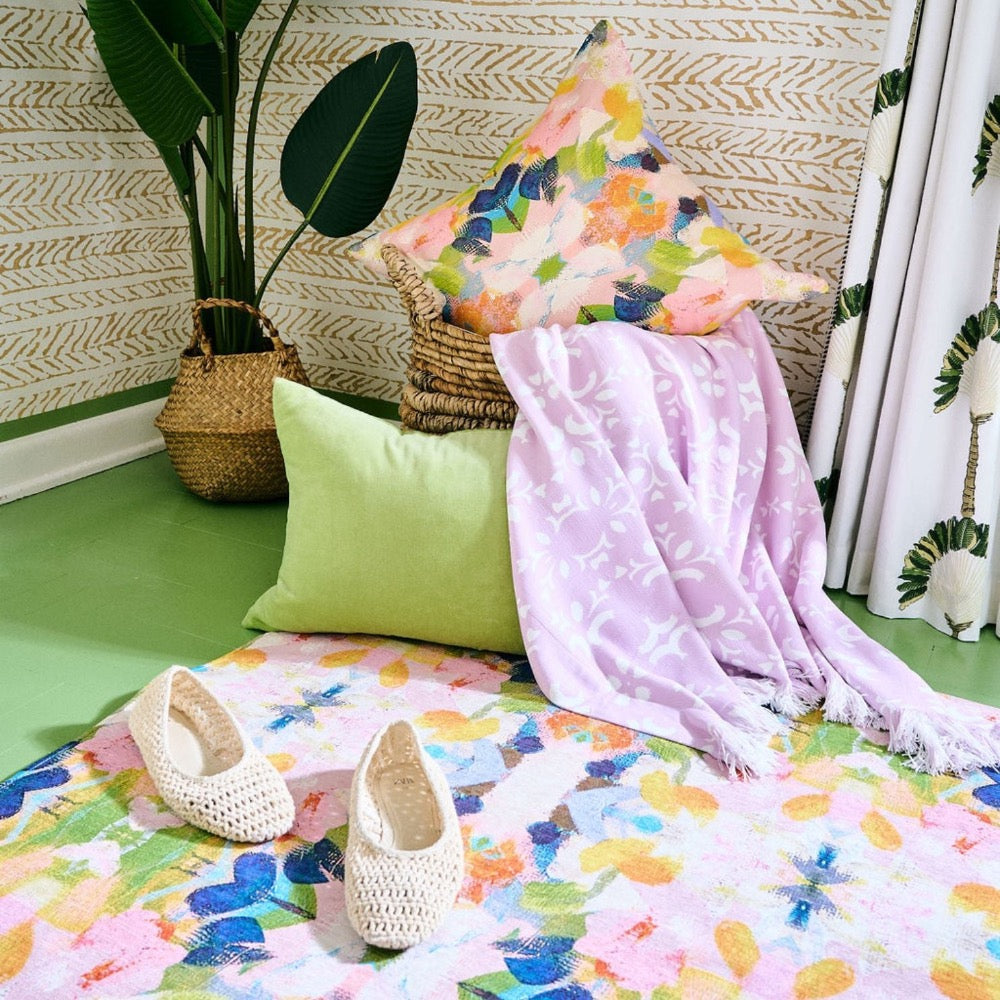 Cozy corner with pillows, blanket, basket, leafy decor on Laura Park Designs' Color Me Happy Floor Mat.
