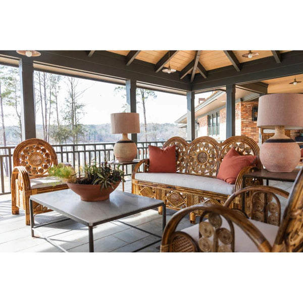 Outdoor patio furniture set with wicker chairs and table on a covered deck.