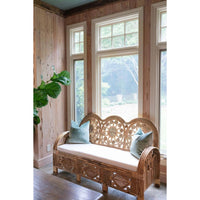 Wicker bench with cushions in a room with wooden walls and large windows.