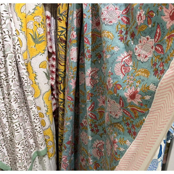 Seaside Bouquet Cabana Tablecloth by Abigails, featuring colorful floral prints, hangs among patterned fabrics.