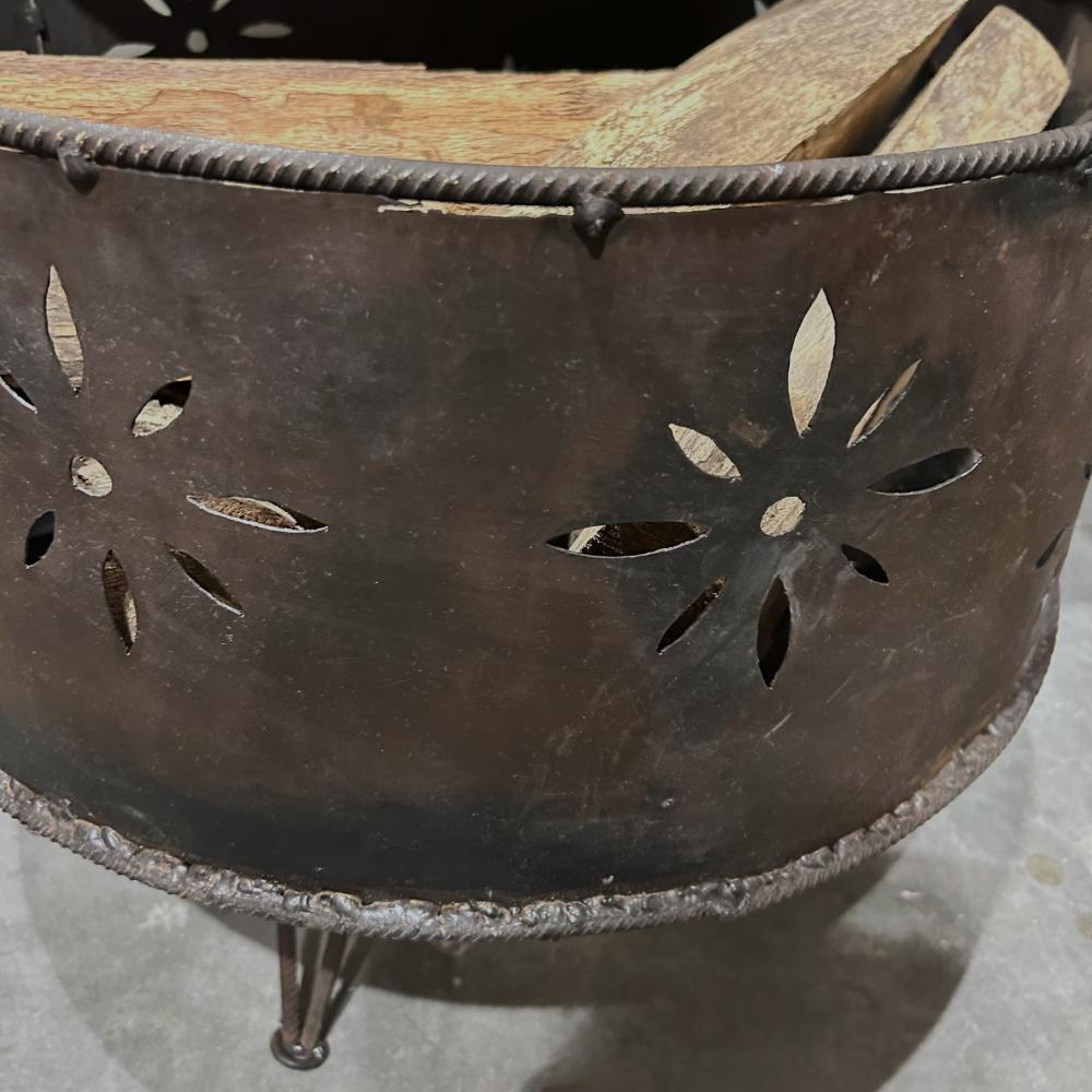 Metal fire pit with decorative cutouts and wooden logs on a concrete surface