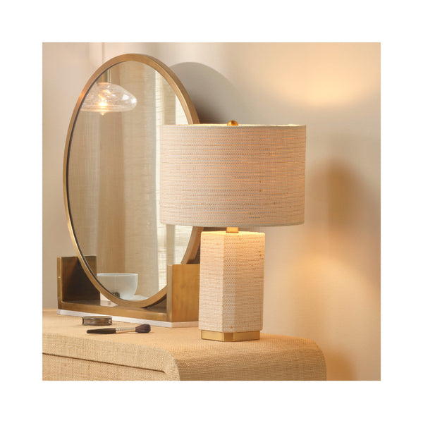Decorative lamp with textured shade and round mirror on a table.