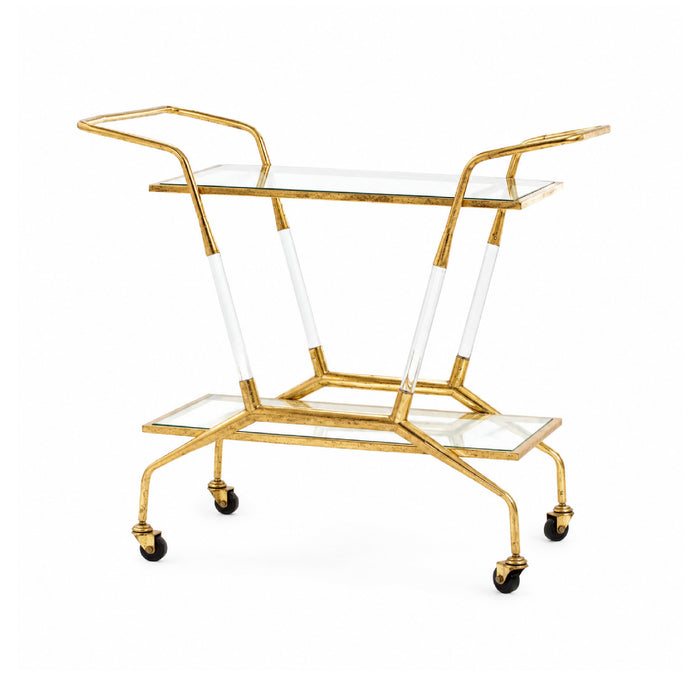 The Jepson Clear + Gold Leaf Bar Cart by Villa & House features acrylic accents, two shelves, and four wheels.
