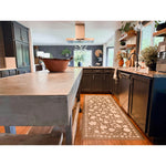 Modern kitchen with dark cabinets, concrete island, and Spicher and Company floral vinyl mat on wood floors.