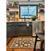 A modern kitchen with dark cabinets, open shelves, and a Spicher and Company floral vinyl mat under the sink window.