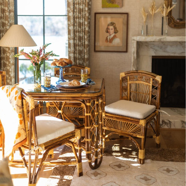 Dining room with wicker table and chairs, lamp, and decorative elements.