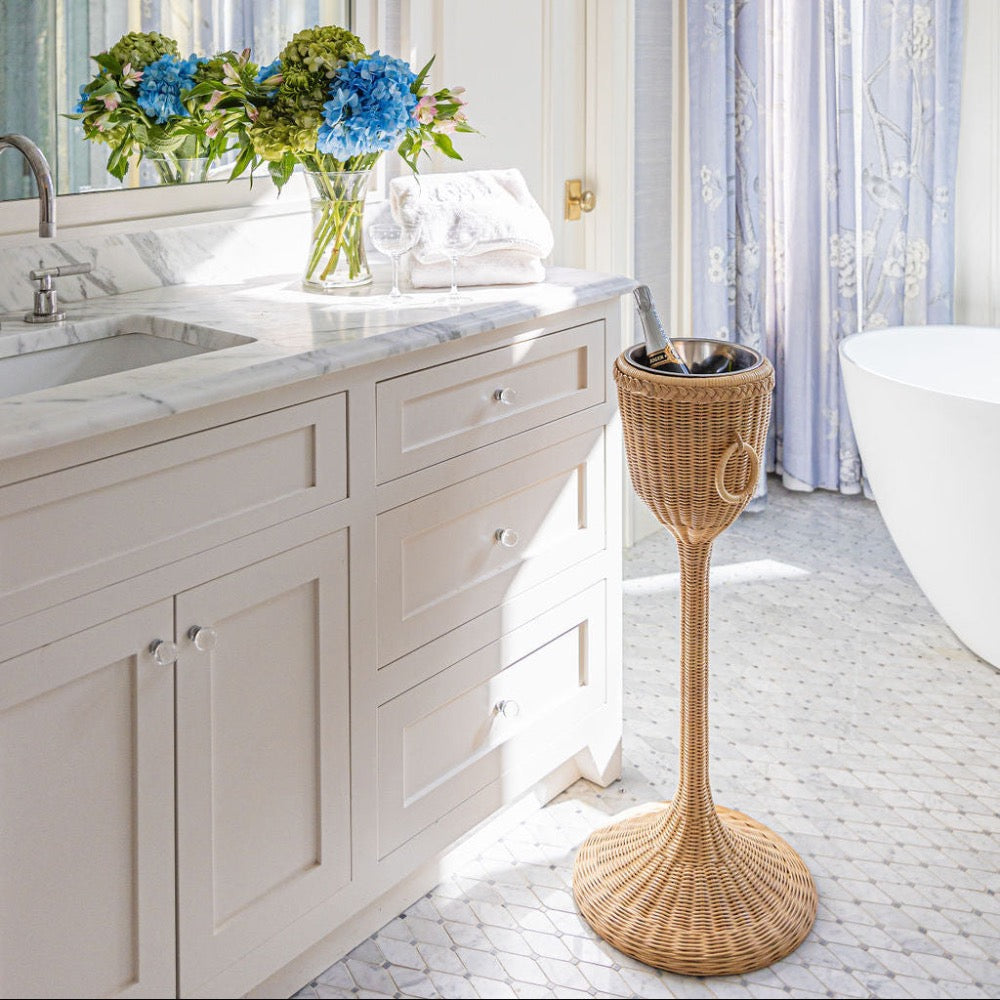 Bathroom with marble vanity, wicker champagne stand, and bathtub.