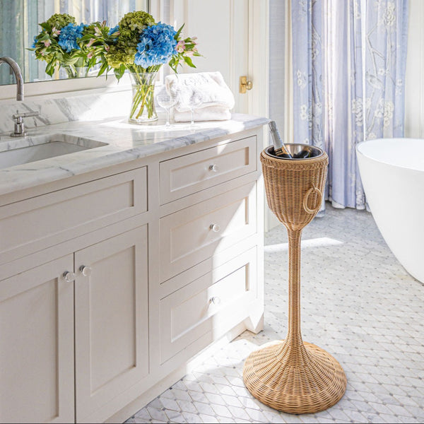 Bathroom with marble vanity, wicker champagne stand, and bathtub.