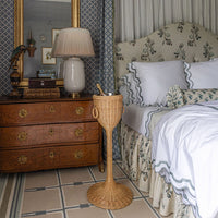 Bedroom with wooden dresser, lamp, and wicker champagne stand.