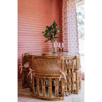 Wicker dining table with chairs against a pink wall