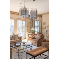 Living room with beige sofa, armchair, and ottoman with a glass coffee table.
