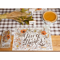 Thanksgiving table with Hester & Cook Give Thanks Paper Placemats, pumpkin pie, wheat bouquet, and holiday decor.
