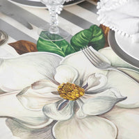 A Magnolia Die Cut Paper Placemat by Hester & Cook on a striped table set with a fork, plate, and glass.