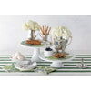A table set with flowers, pastries, and decorative items on white cake stands and a Dark Green Classic Stripe Paper Runner by Hester & Cook.