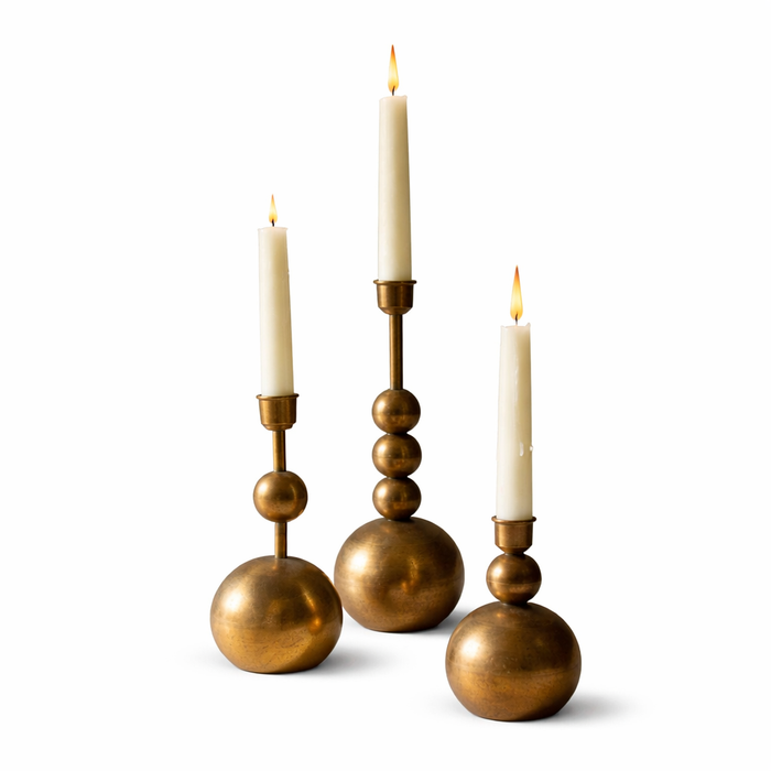 Three gold candle holders with candles on a white background