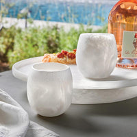 Santa Barbara Design Studio Resin White Stemless Wine Glasses (set of 4) on an outdoor table by the water.