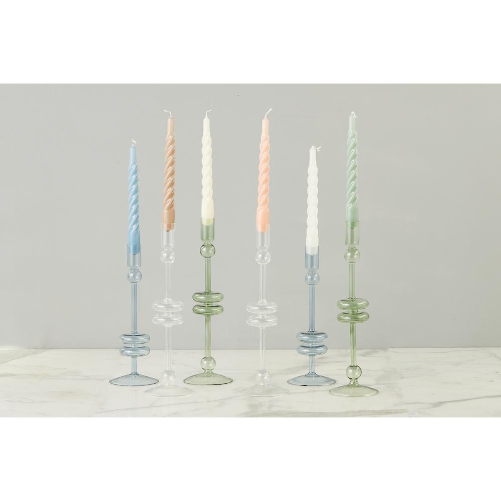 Set of glass candle holders with candles on a light gray background