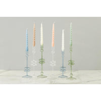 Set of glass candle holders with candles on a light gray background