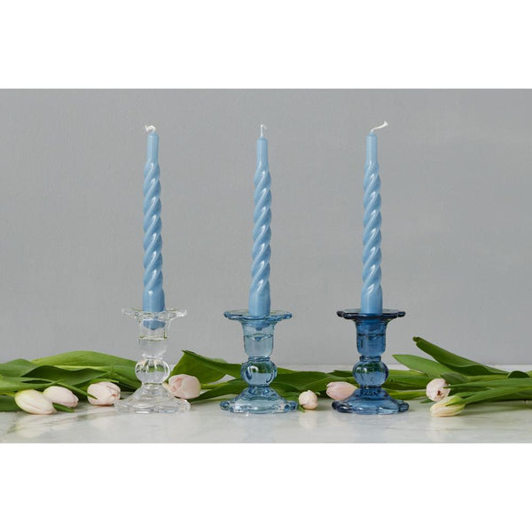 Three blue twisted candles in decorative holders with tulips on a gray background
