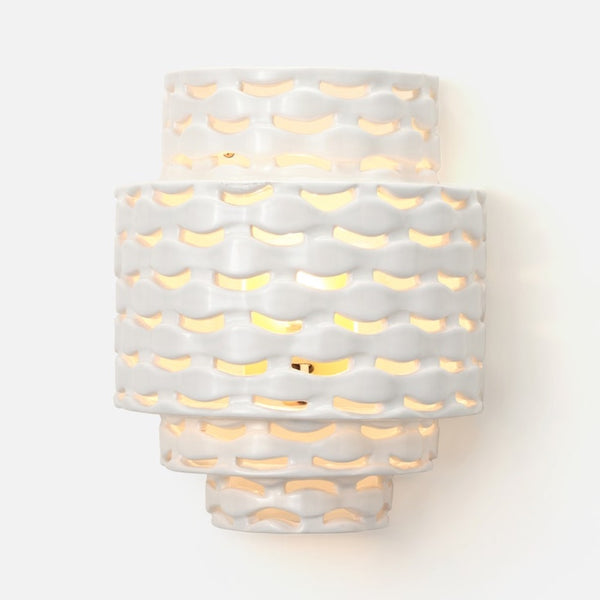 The Made Goods Omiros White Gloss + Gold Sconce features wavy layers and warm light shining through abstract cutouts.