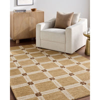 A rectangular area rug with a beige, cream, and brown plaid pattern, styled in a living room setting next to a cream armchair and a light wood cabinet.