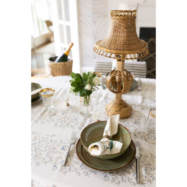 Elegant table setting with a woven lamp, plates, and cutlery on a floral tablecloth.
