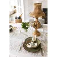 Elegant table setting with a woven lamp, plates, and cutlery on a floral tablecloth.