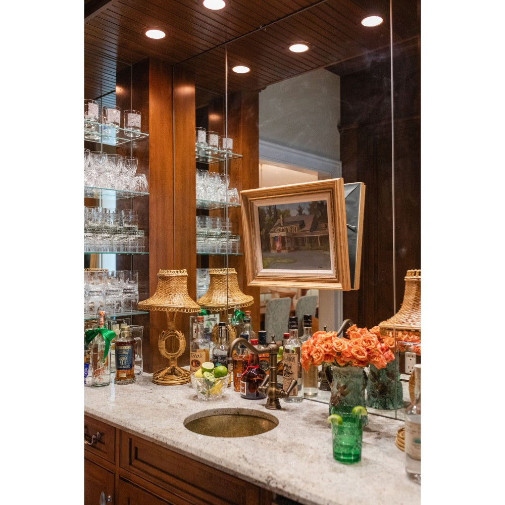 Bar counter with various bottles, glasses, and decorative items in a well-lit room.