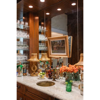 Bar counter with various bottles, glasses, and decorative items in a well-lit room.
