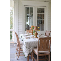 Dining table set with chairs on a patio with a white house exterior.