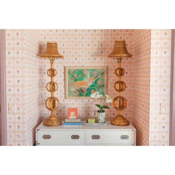 Decorative room with two tall lamps, a cabinet, and a painting on a wall with floral pattern.