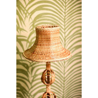 Wicker lamp with a textured shade against a green patterned wall