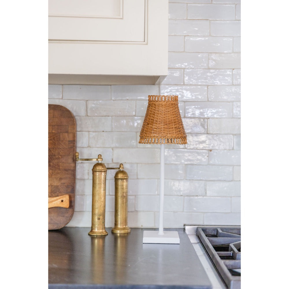 Kitchen counter with brass pepper mills, wooden cutting board, and lamp against a tiled wall.