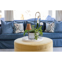 Blue sofa with decorative pillows and a yellow ottoman in a living room setting.